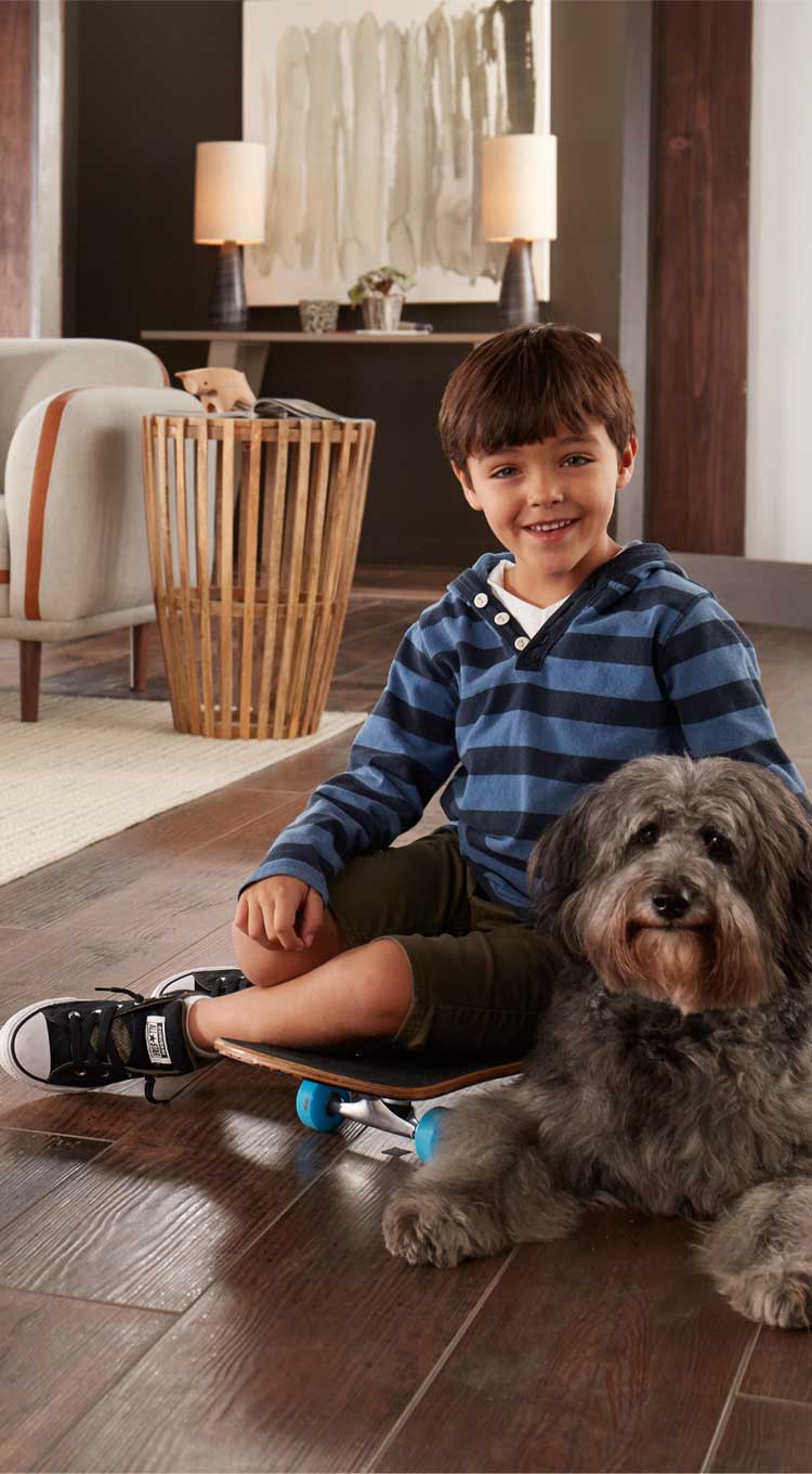 boy and dog sitting on hardwood floor